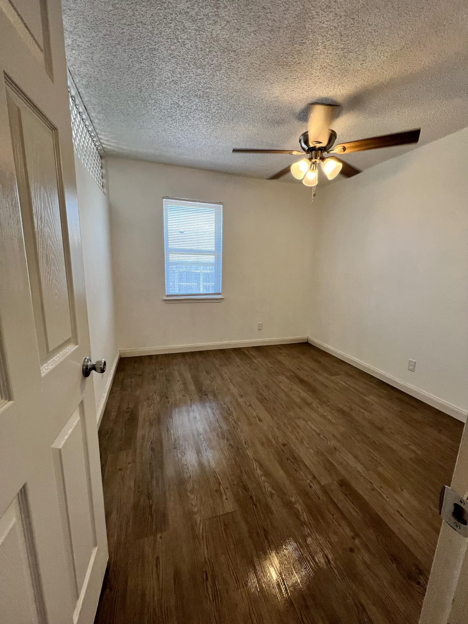 An empty bedroom with hardwood floors and a ceiling fan.