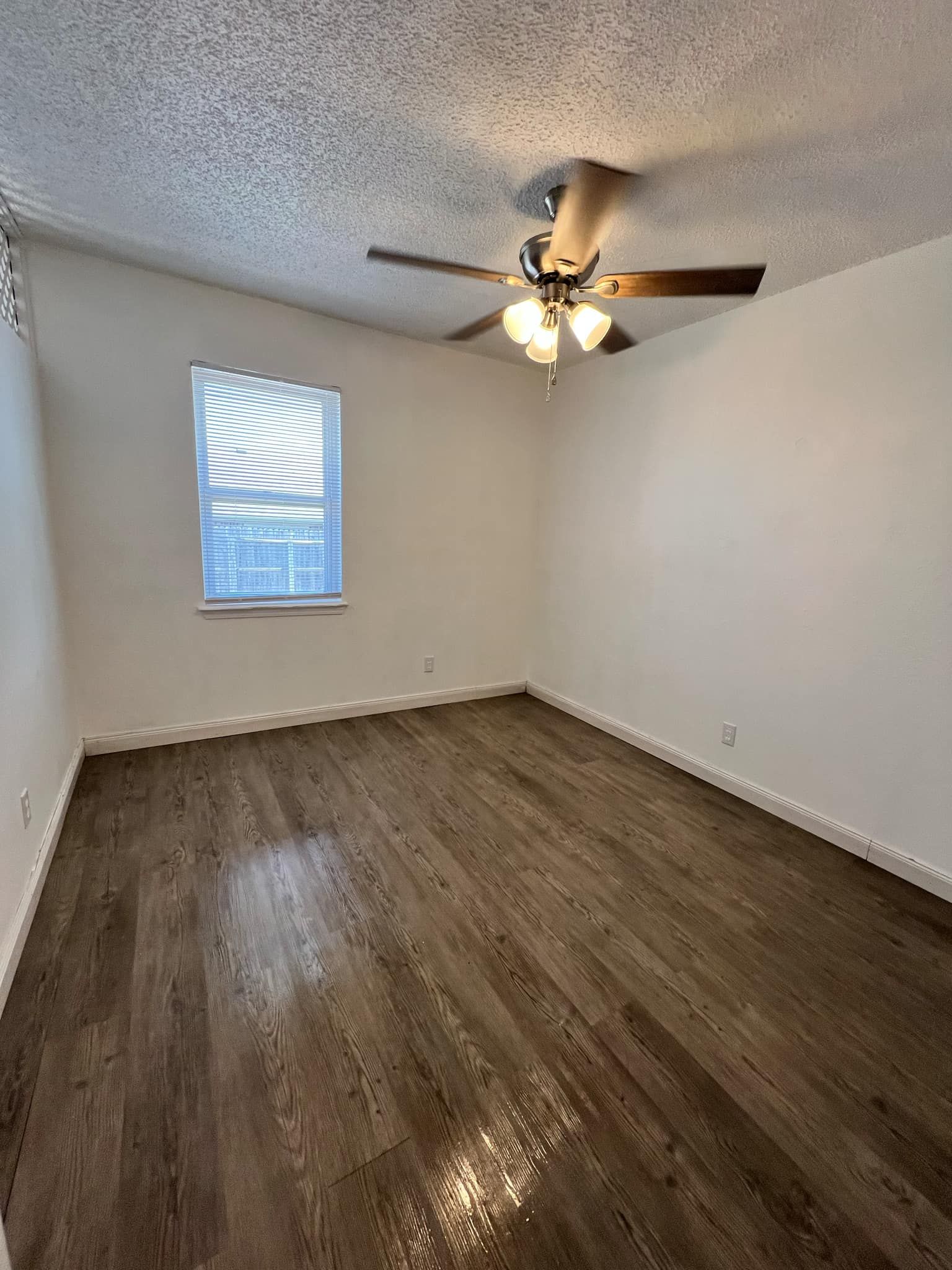 An empty bedroom with hardwood floors and a ceiling fan.