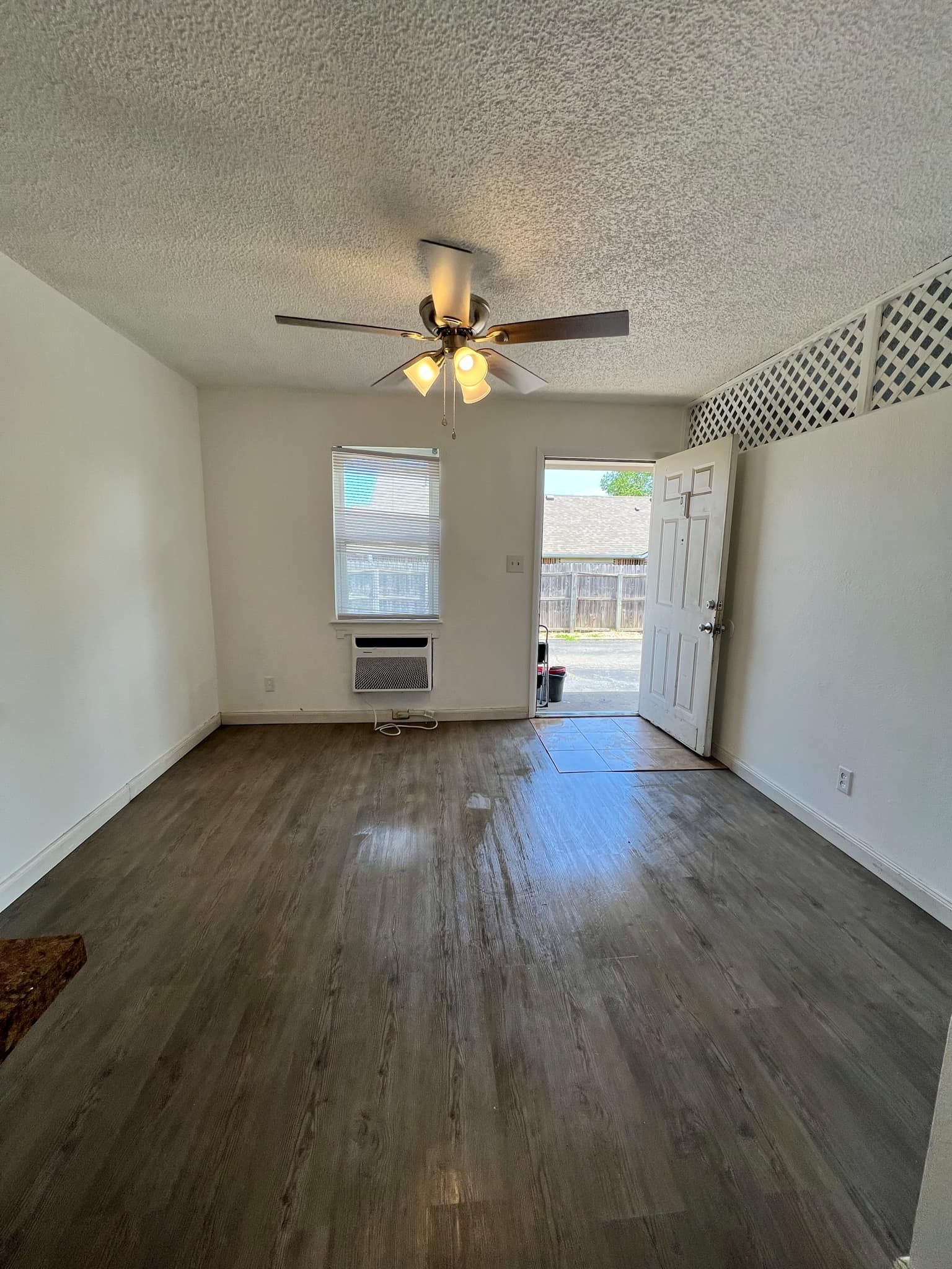 An empty living room with hardwood floors and a ceiling fan.