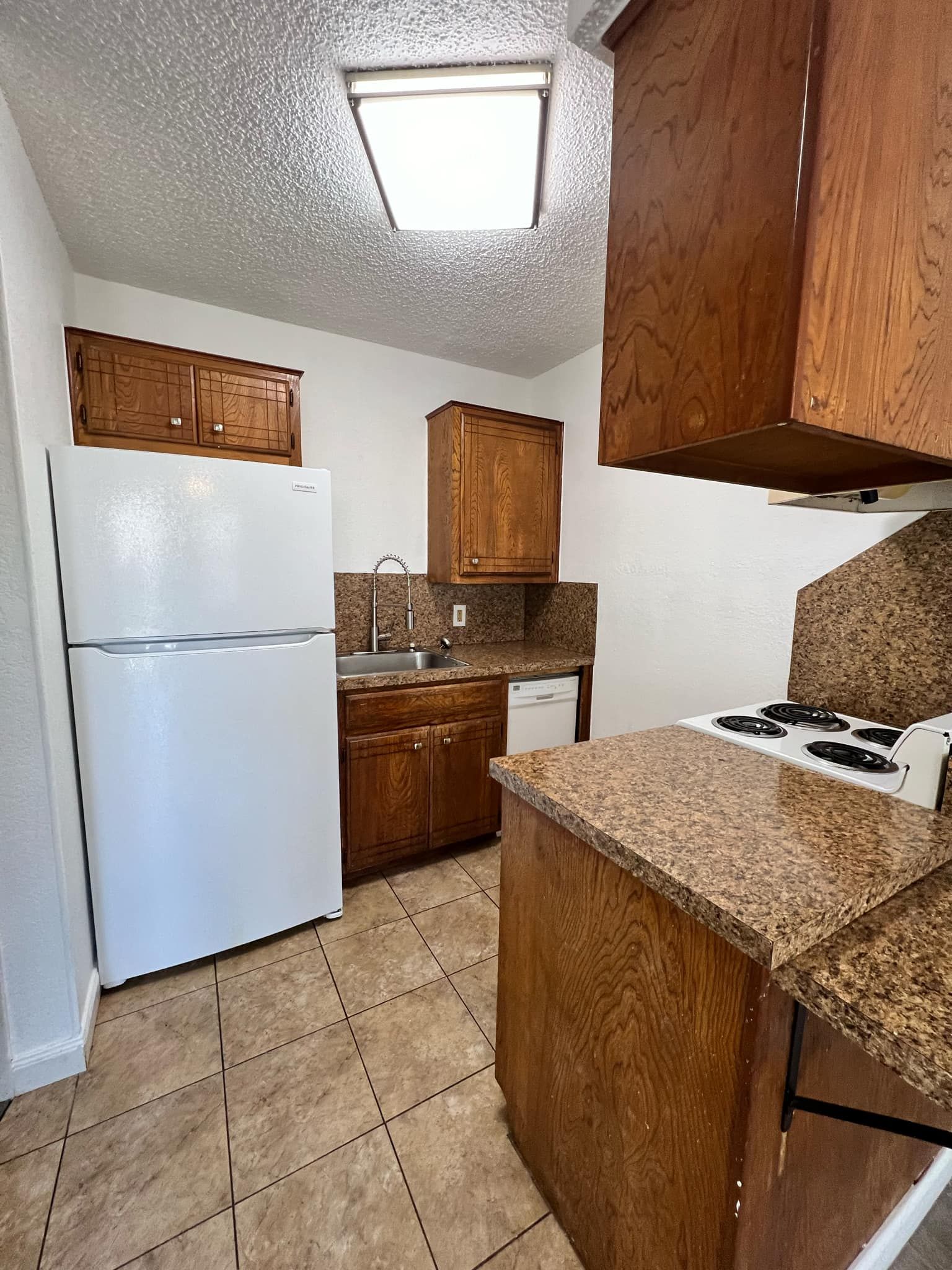A kitchen with a refrigerator , stove , sink and cabinets.