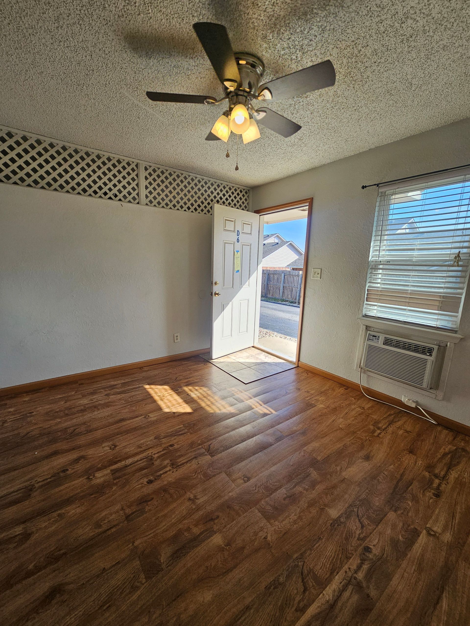 An empty room with a ceiling fan and a window.