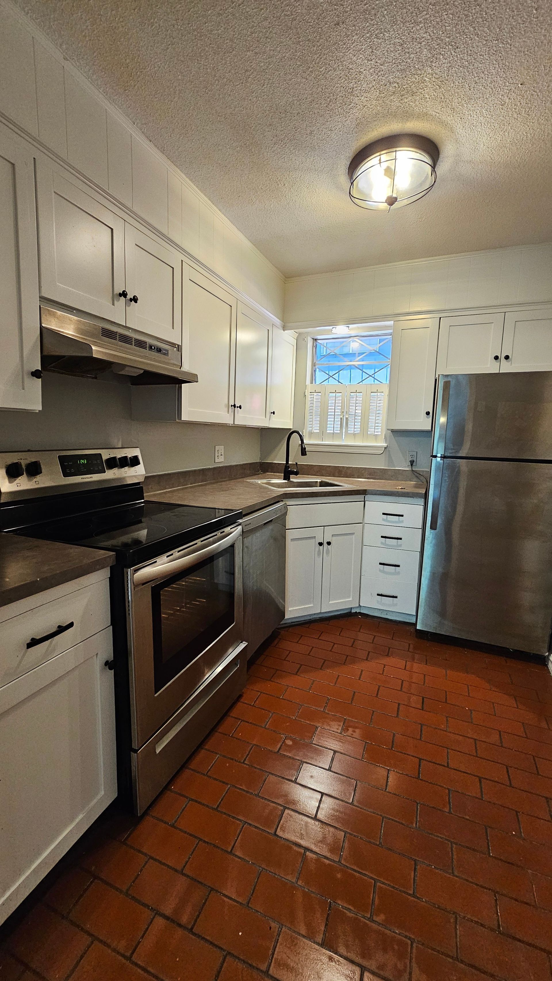 A kitchen with stainless steel appliances and white cabinets.