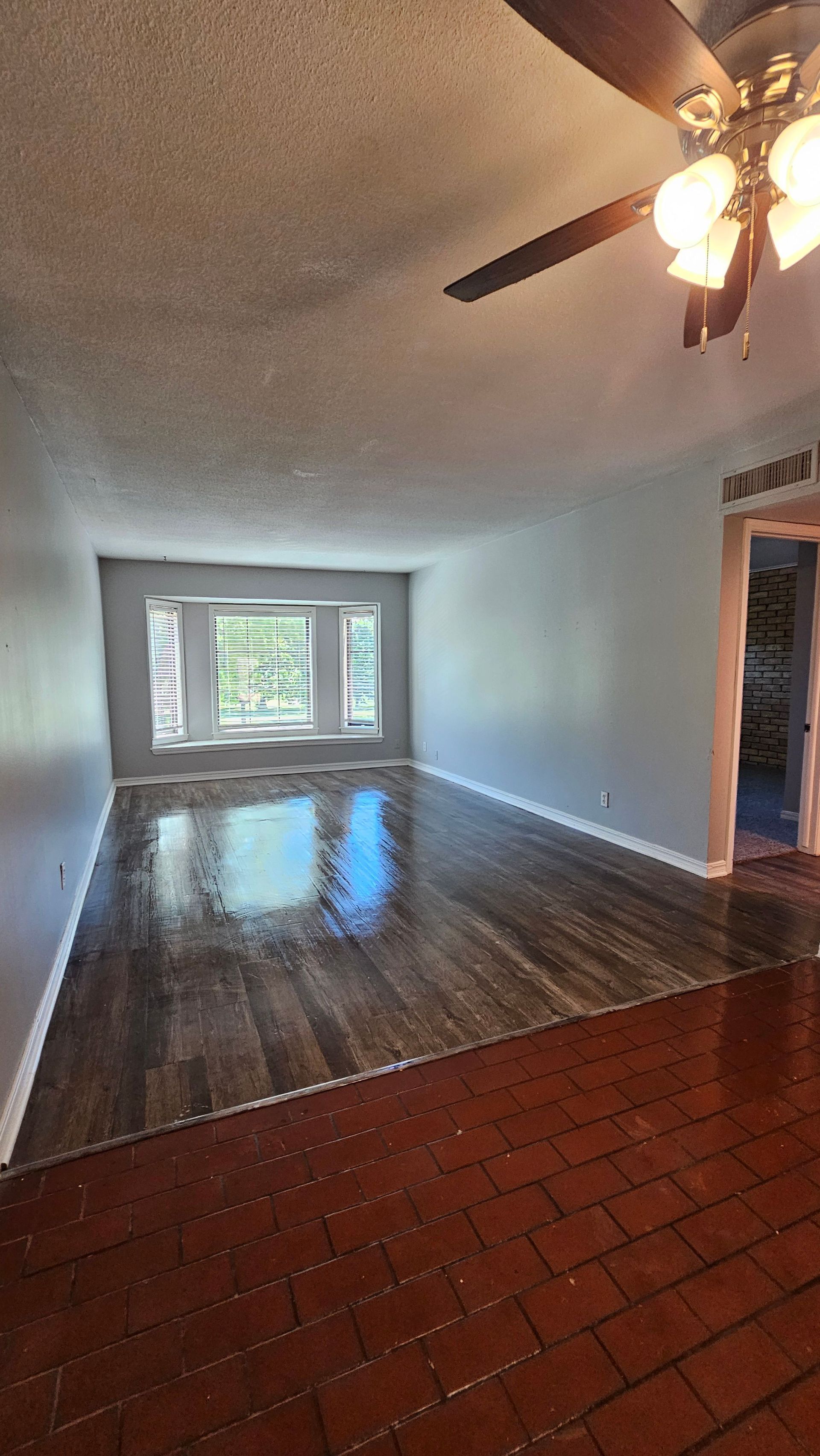 A living room with hardwood floors and a ceiling fan.