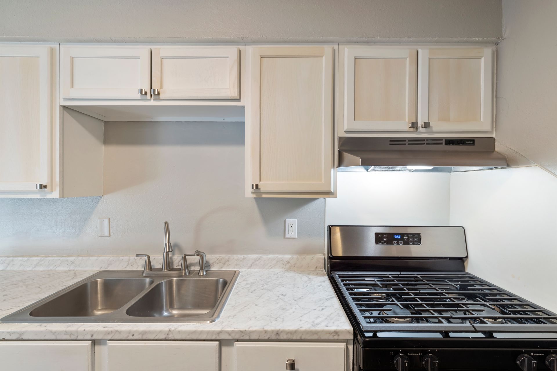 A kitchen with a stove , sink , and cabinets.