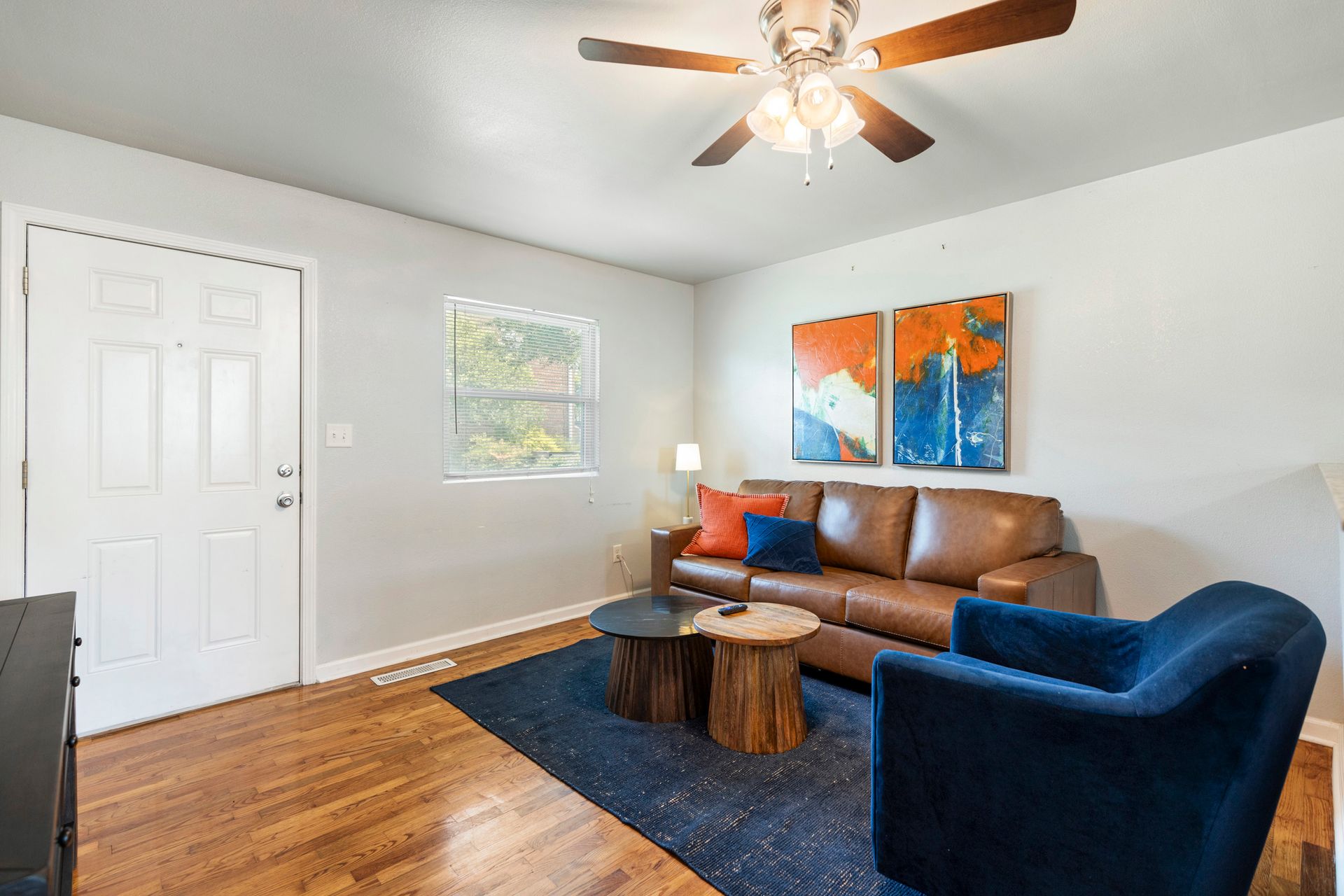 A living room with a couch , chair , table and ceiling fan.