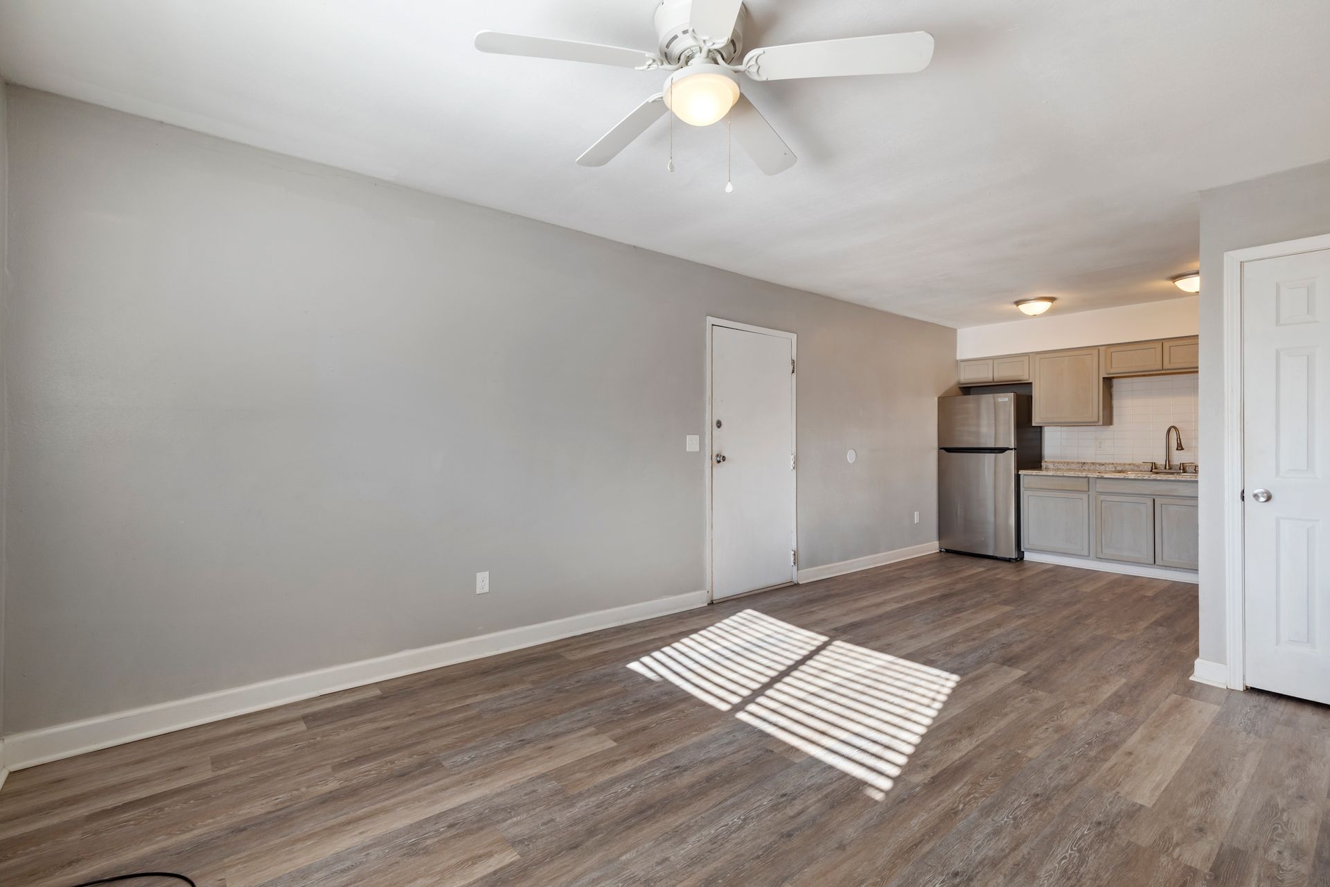 A living room with hardwood floors and a ceiling fan.