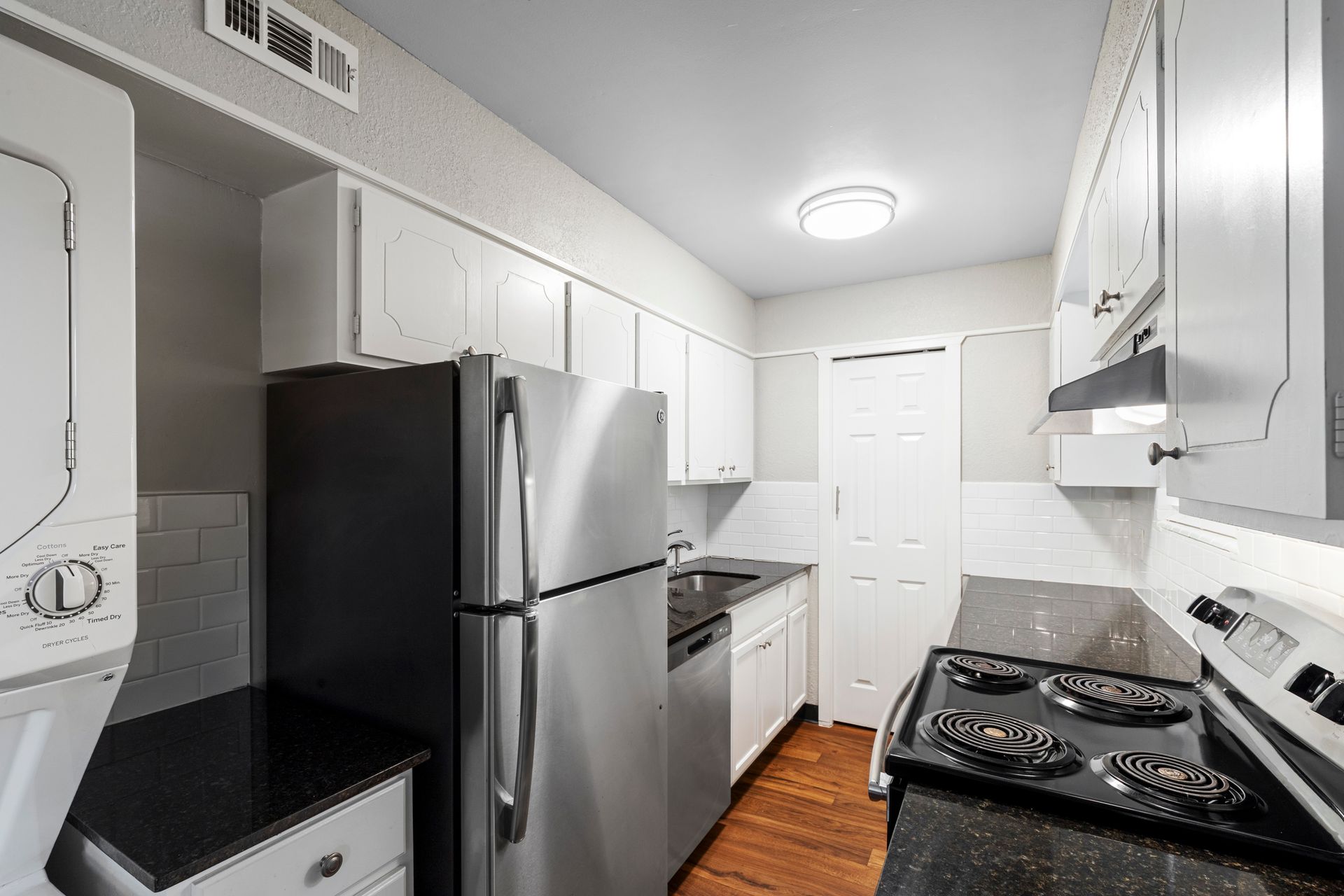 Small kitchen with stainless steel appliances, white cabinets, and dark countertops.