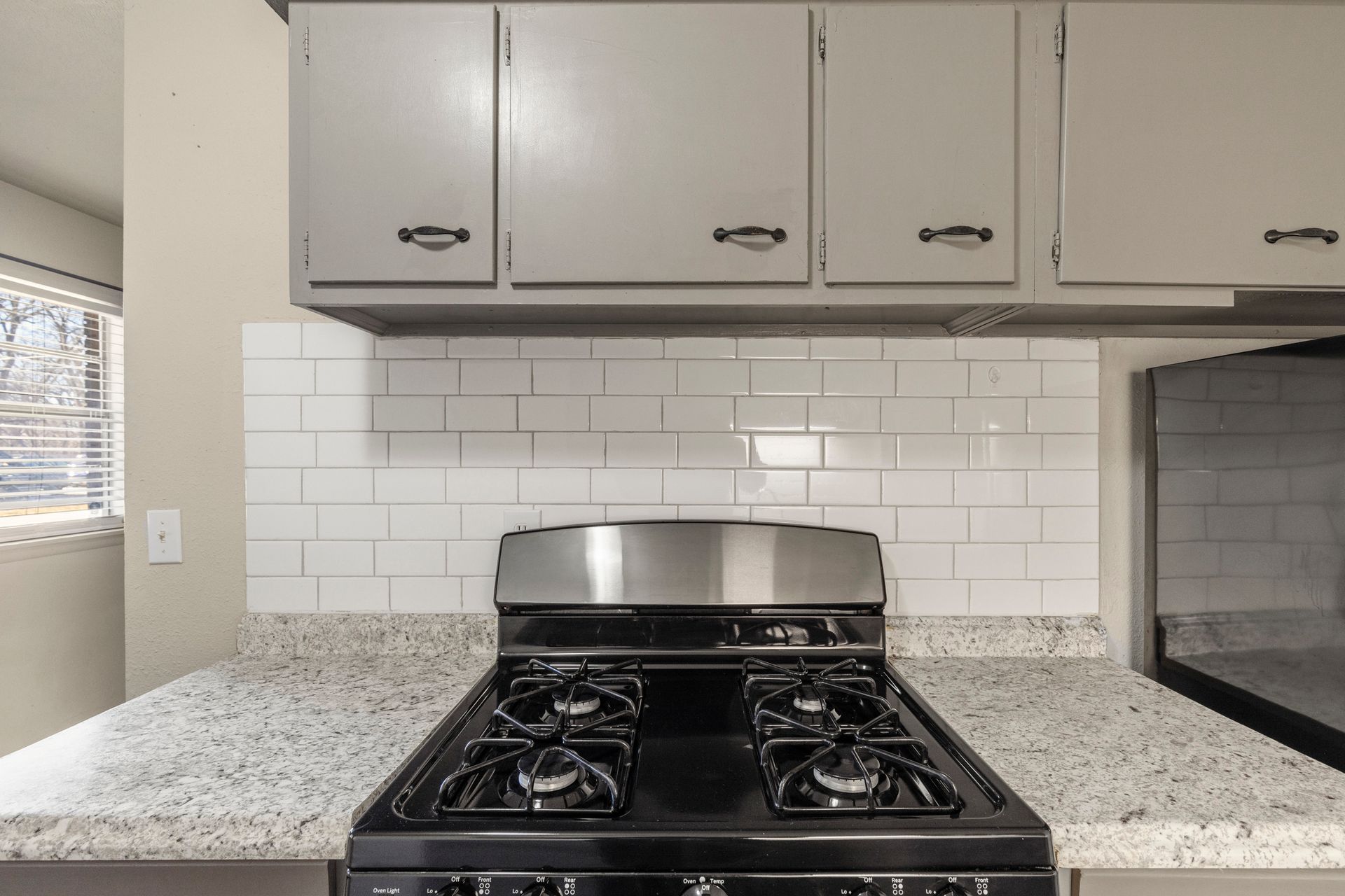 A stove top oven is sitting on top of a granite counter in a kitchen.