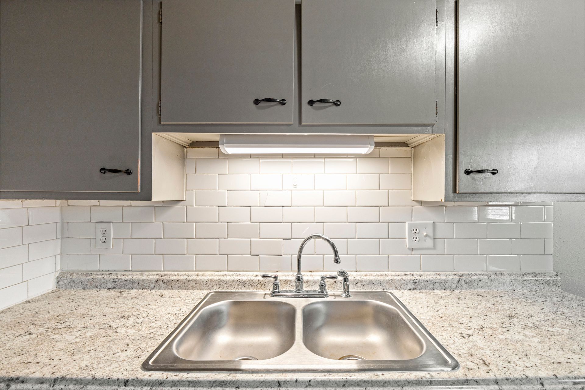 A kitchen with a stainless steel sink and a faucet