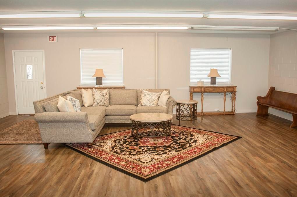 Living room with neutral walls, sectional sofa, area rug, windows, and bench.