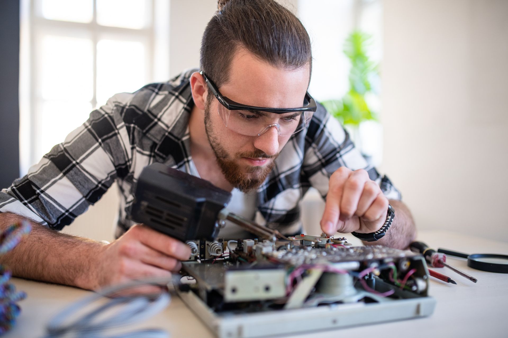 Man with safety glasses soldering circuit board, indoors. Man with safety glasses soldering circuit board, indoors.