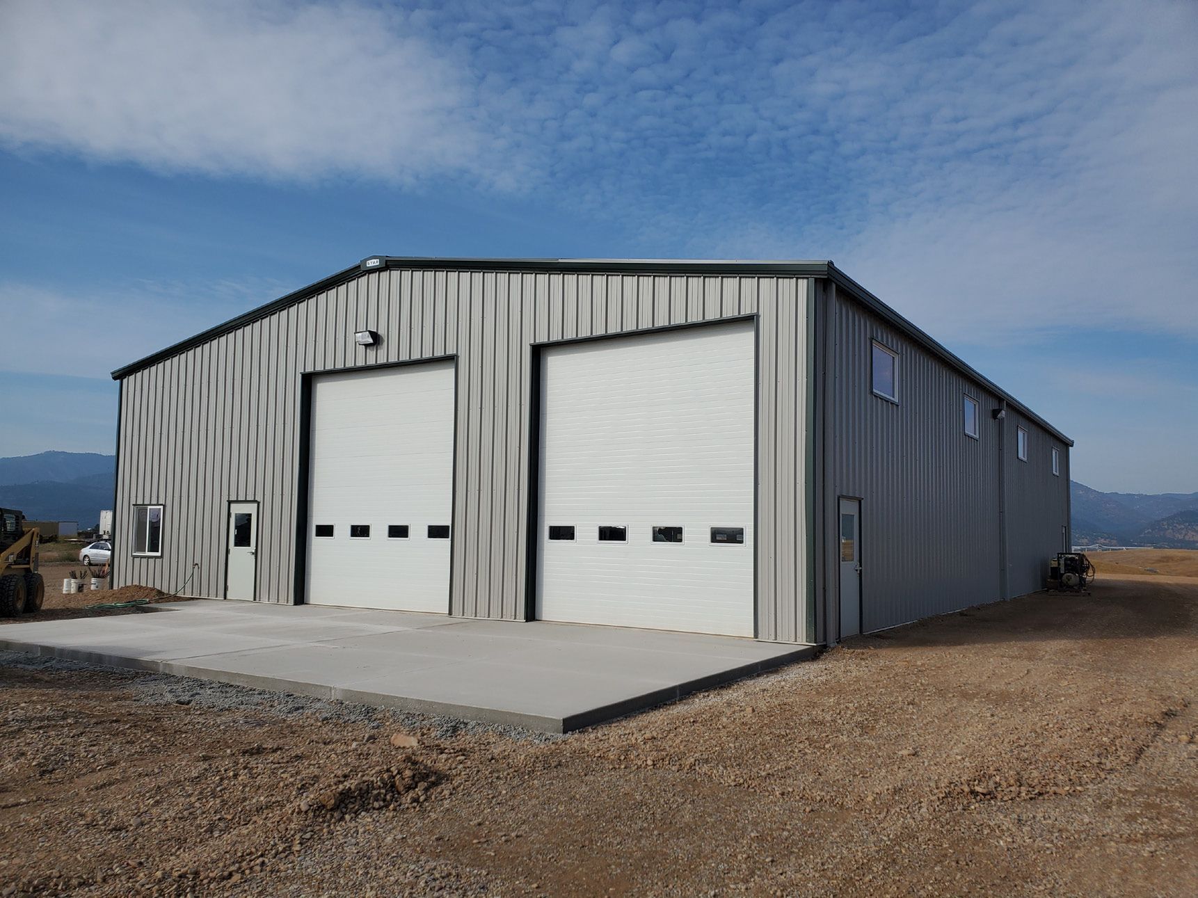 A large metal building with two white garage doors