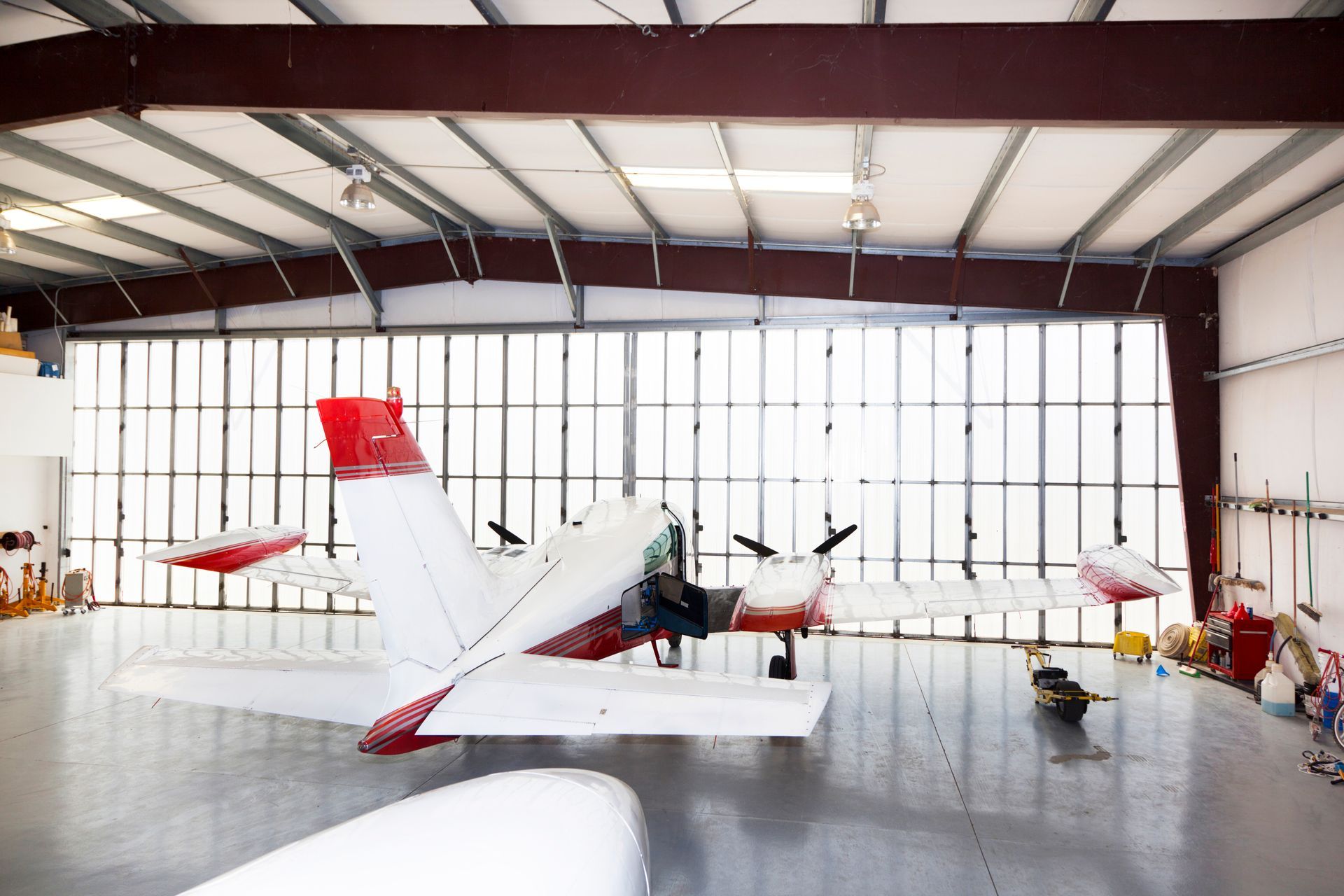 A small red and white plane is parked in a hangar