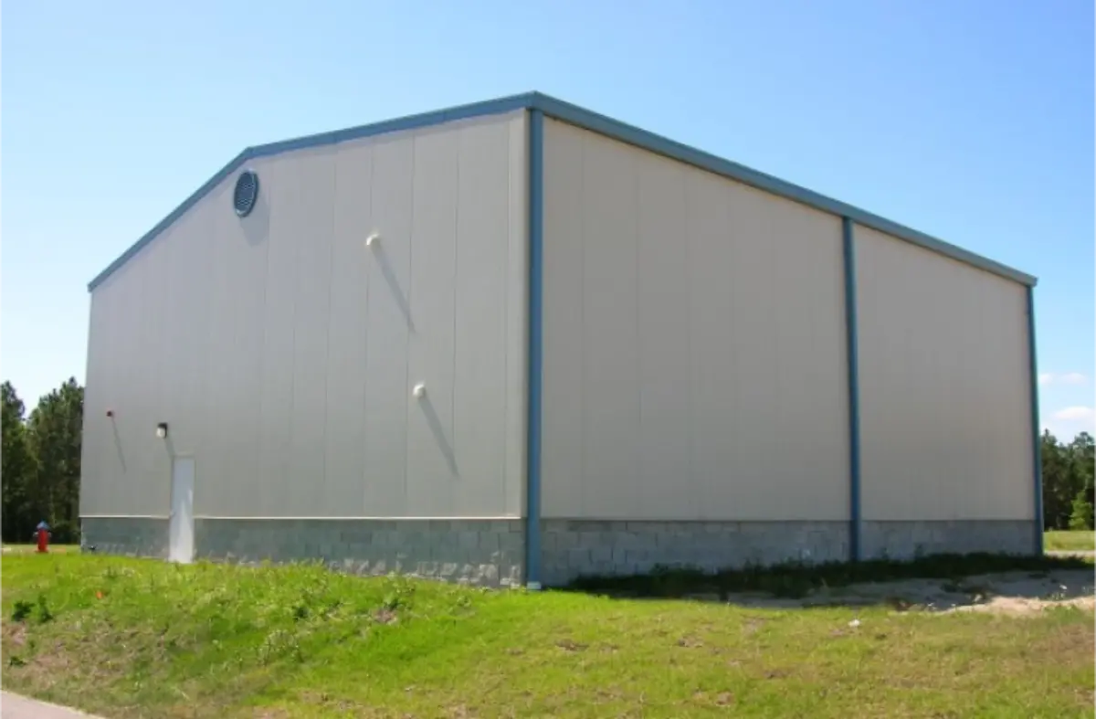 A large white building is sitting in the middle of a grassy field