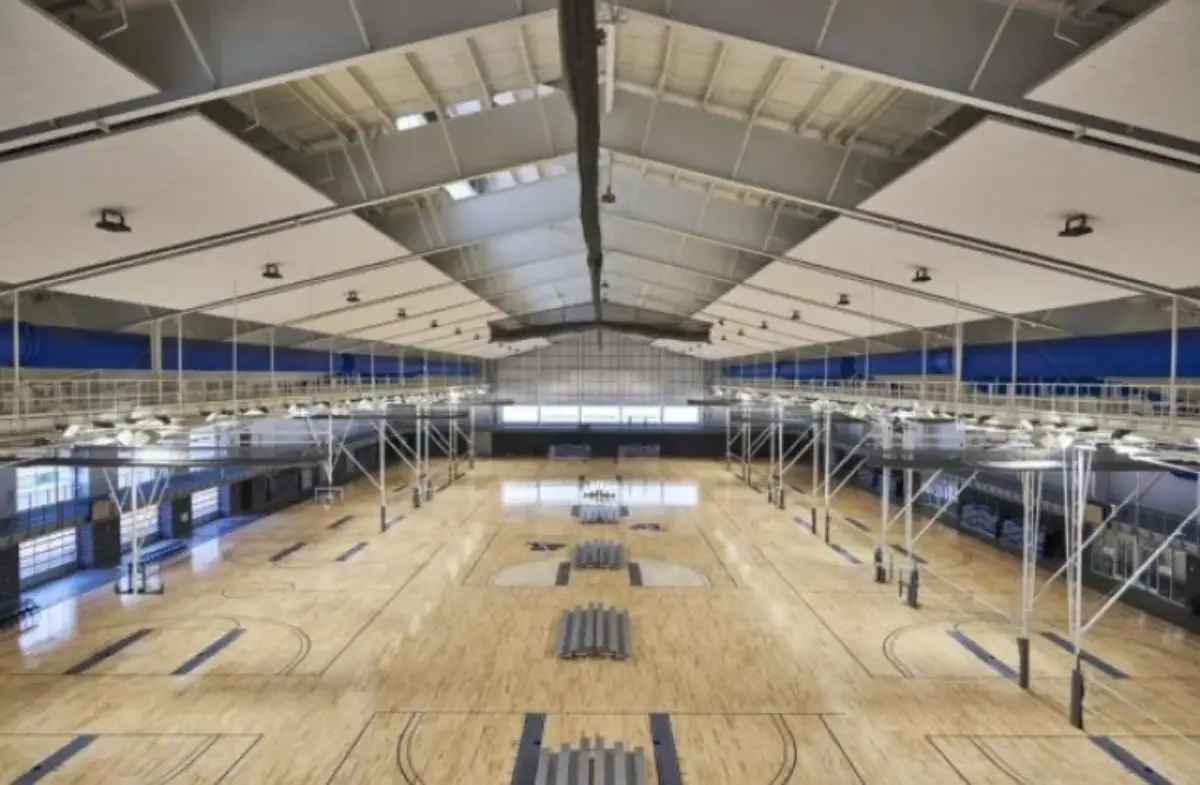 A large indoor basketball court with the letter b on the floor