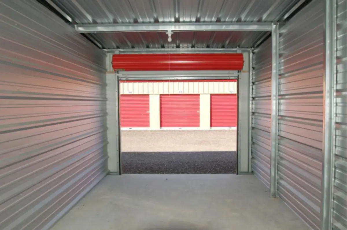 An empty storage unit with a red roller door