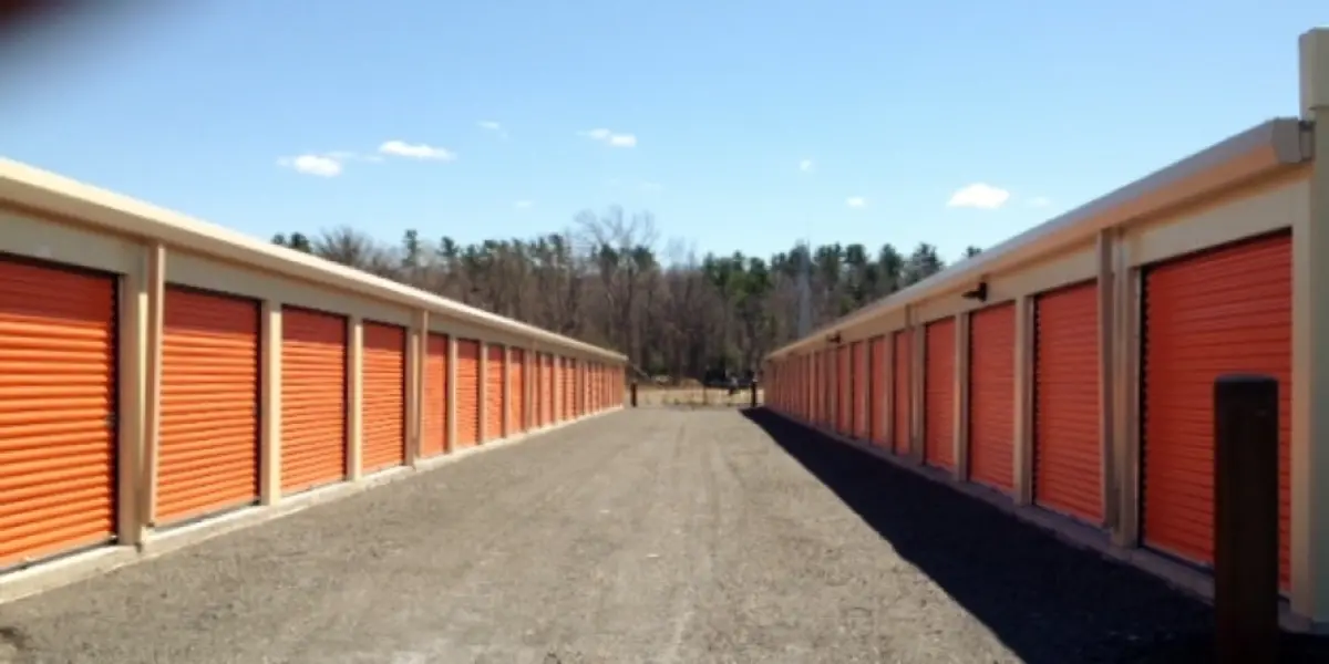 A row of orange storage units on a dirt road