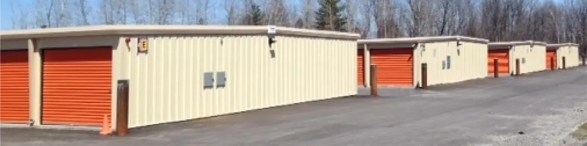 A row of storage units with orange doors are lined up next to each other.