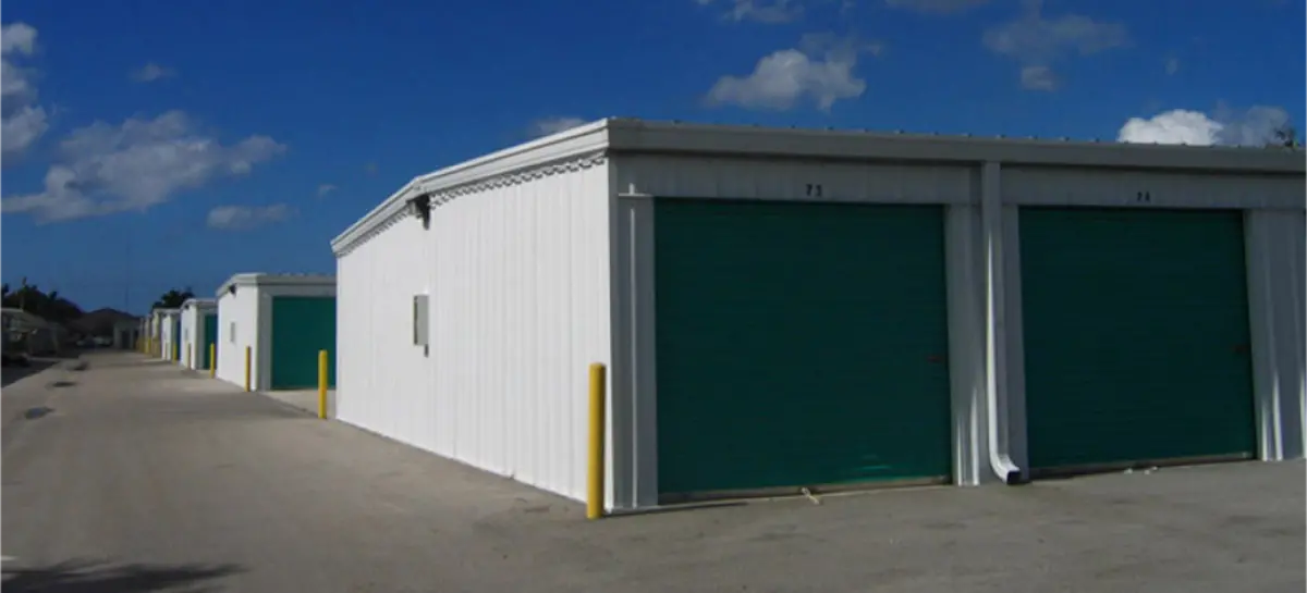 A row of white buildings with green doors on a sunny day.