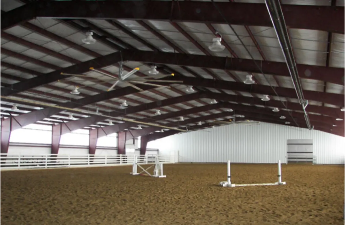 A large indoor arena with a jumping fence in the middle