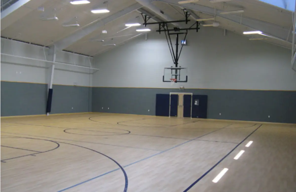 An empty gym with a basketball hoop in the middle