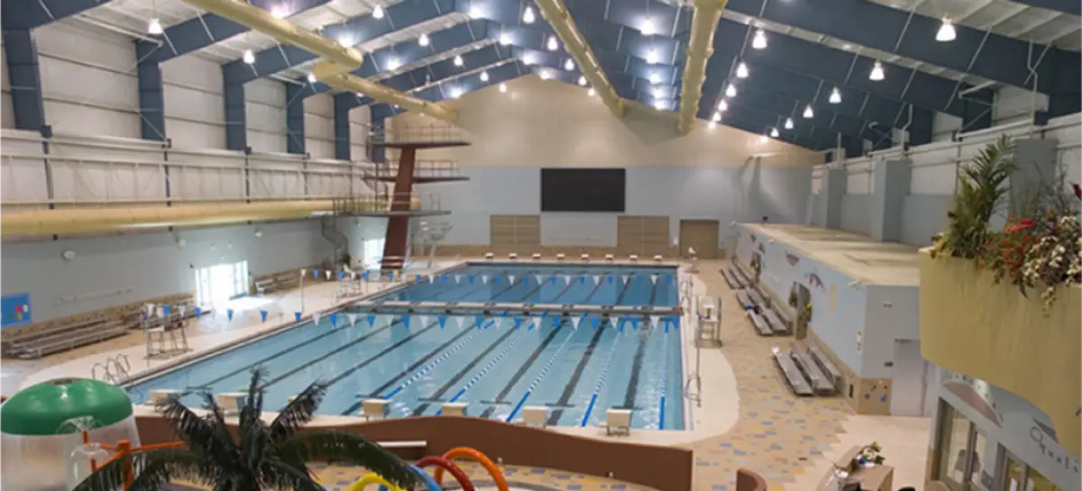 A large indoor swimming pool with a diving board in a building.