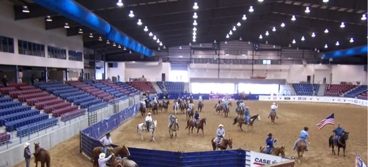 A group of people are riding horses in an arena.