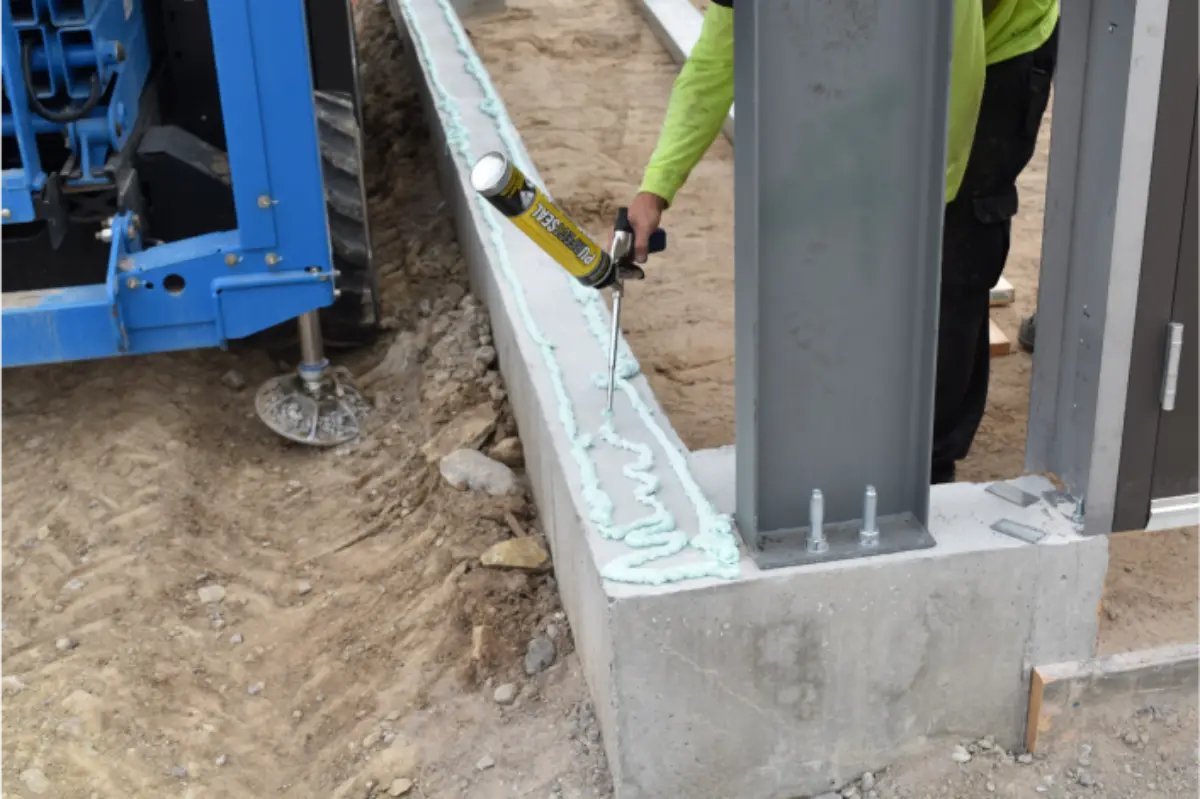 A man is spraying foam on a concrete wall.