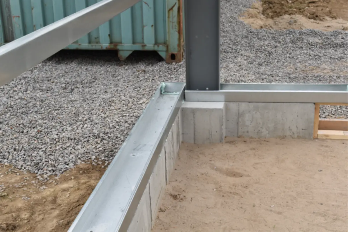 A metal structure is being built on a gravel road.