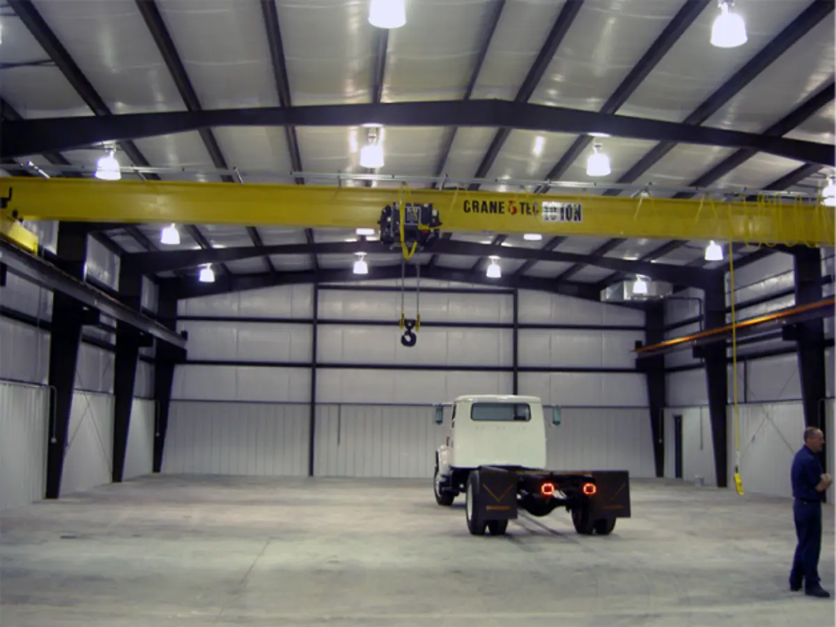 A truck is parked under a crane in a warehouse