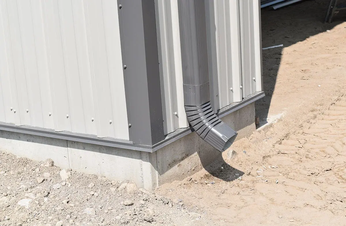 A metal gutter is sitting on the side of a building.