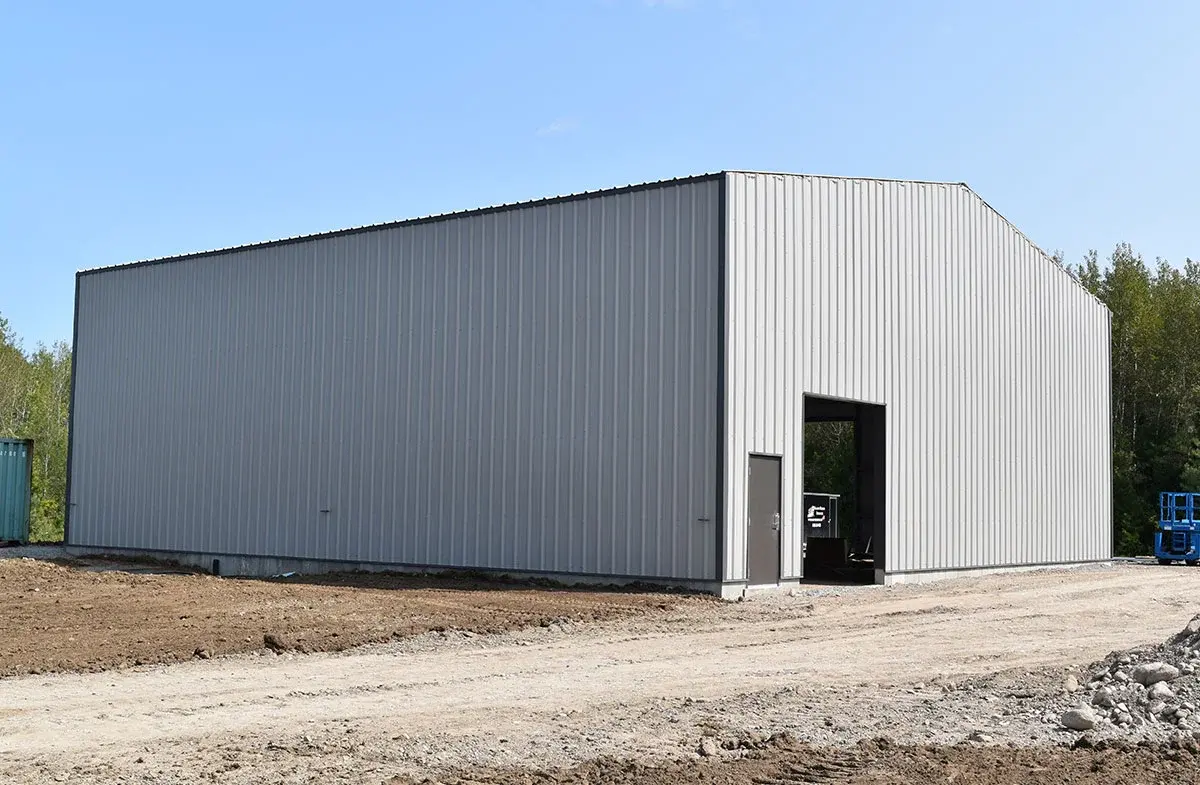 A large white building is sitting in the middle of a dirt field.