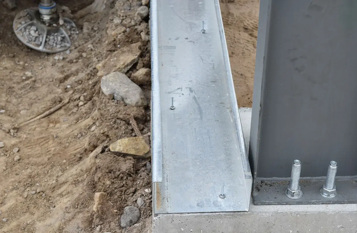 A metal beam is sitting on top of a concrete base.