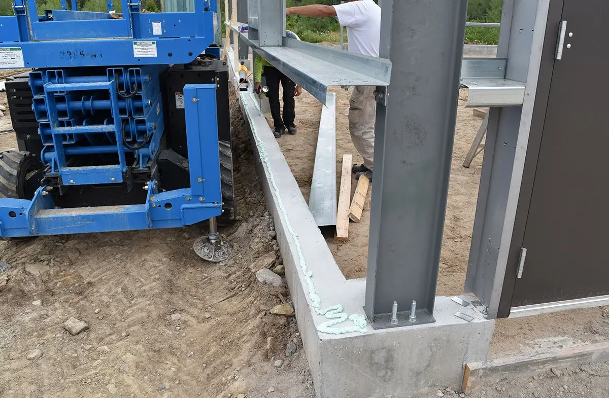 A man is standing next to a blue tractor on a construction site.