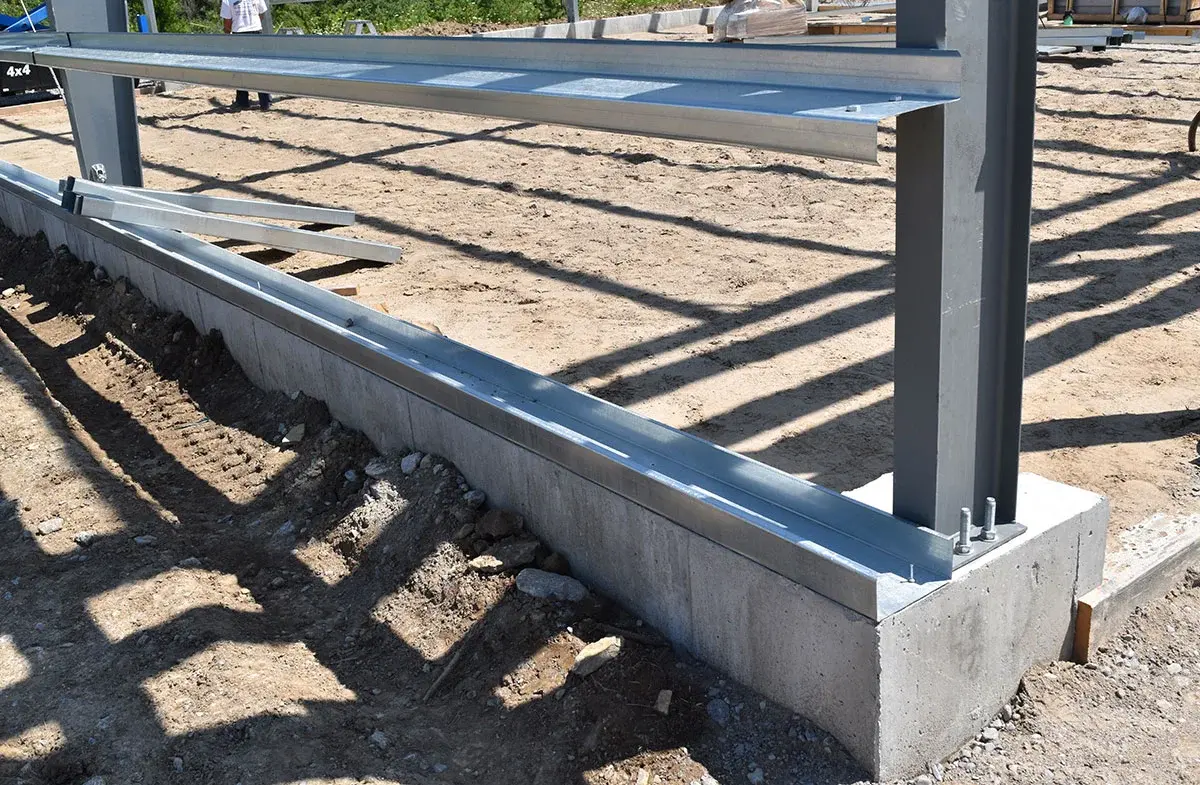 A metal structure is being built on a dirt ground