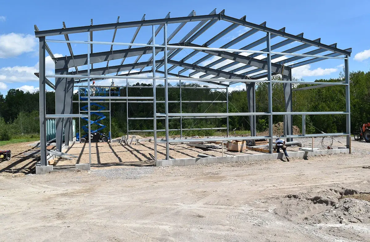 A large metal structure is being built in a dirt field.