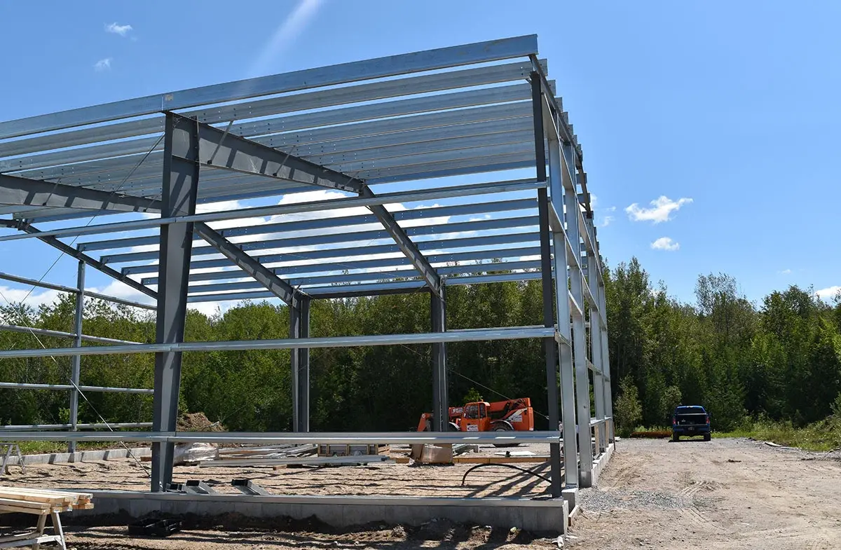 A large metal structure is being built in the middle of a dirt field.