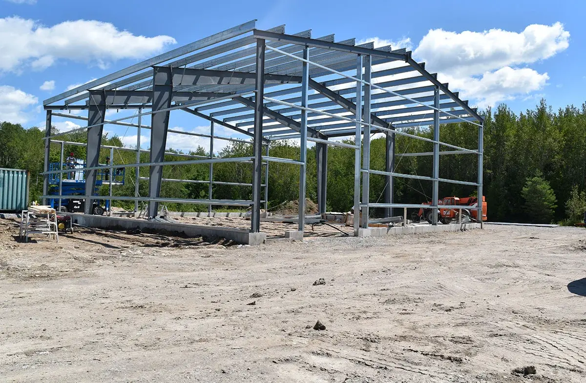 A large metal structure is being built in a dirt field.