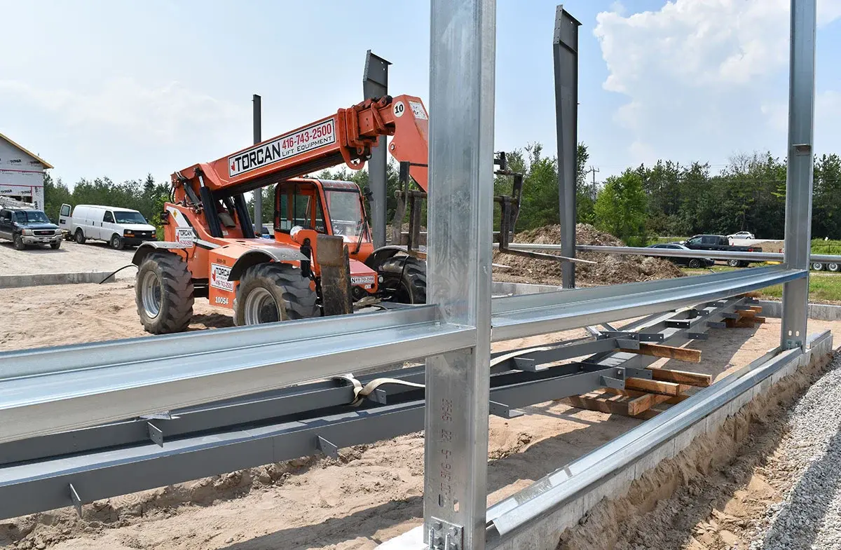 A forklift is moving a metal structure on a construction site.