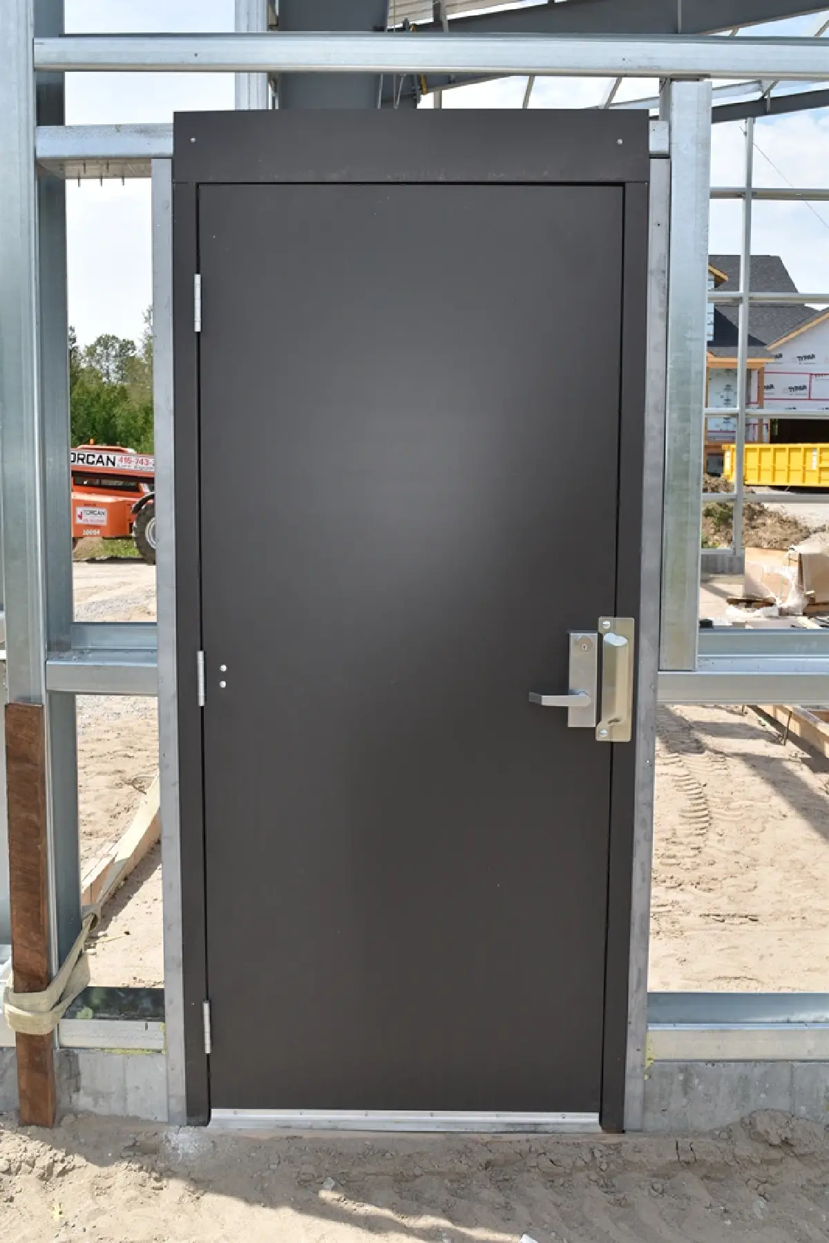 A black door with a silver handle is on a building under construction.