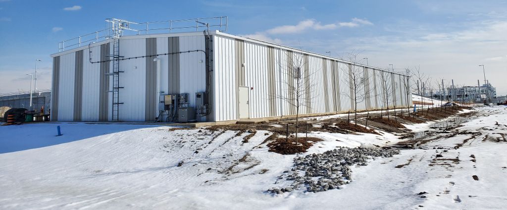 A large white building is sitting in the middle of a snowy field.
