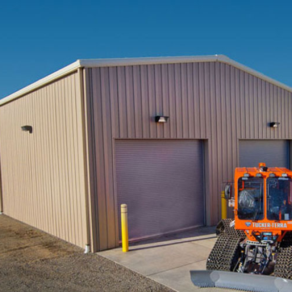 An orange tractor is parked in front of a tan building