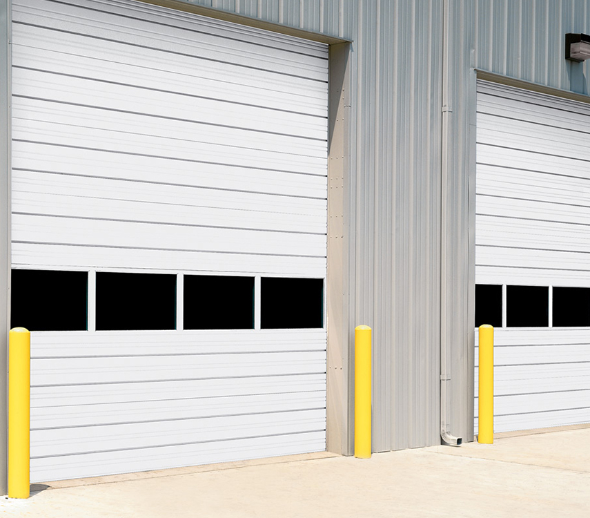 Two white garage doors with black windows are sitting next to each other on the side of a building.