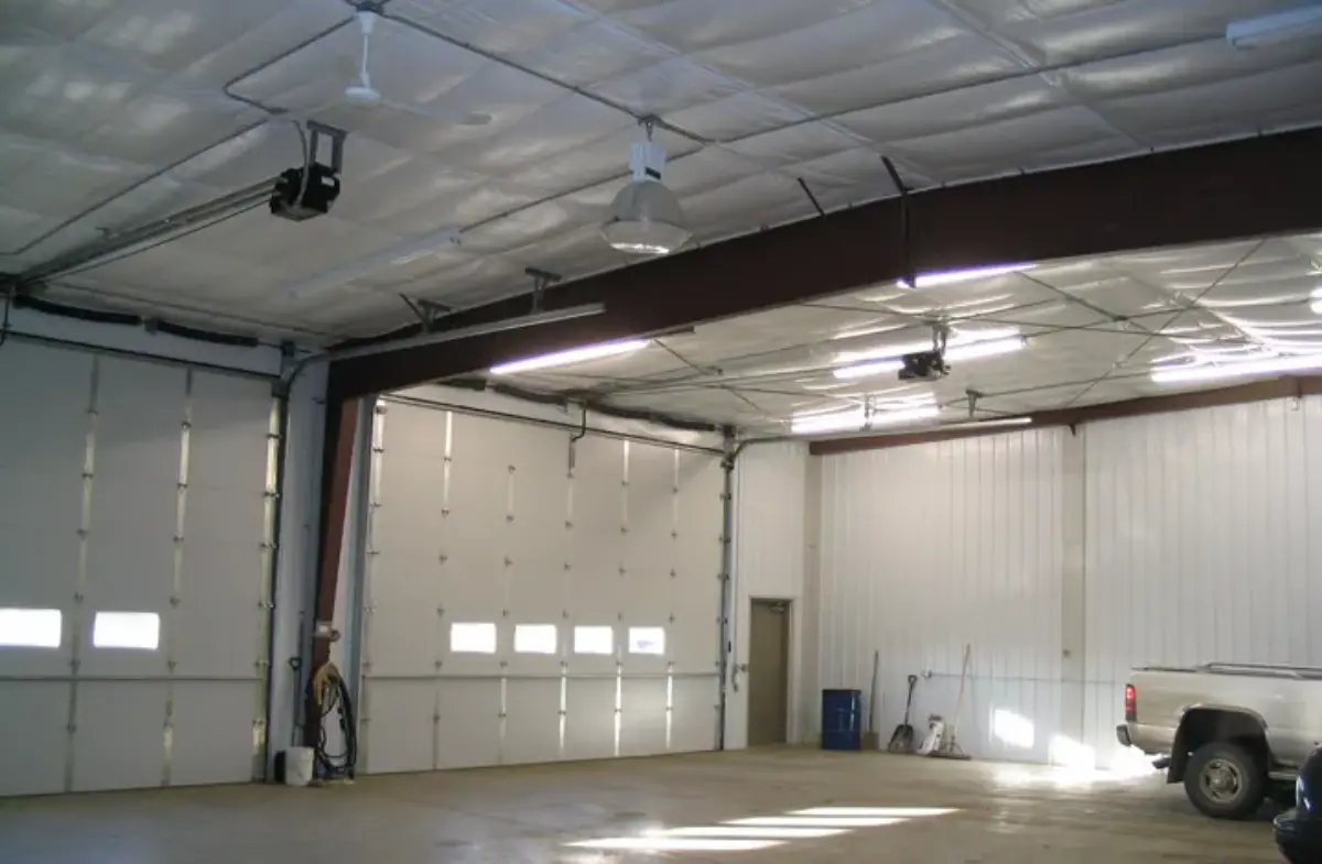 A truck is parked inside of a garage with the doors open