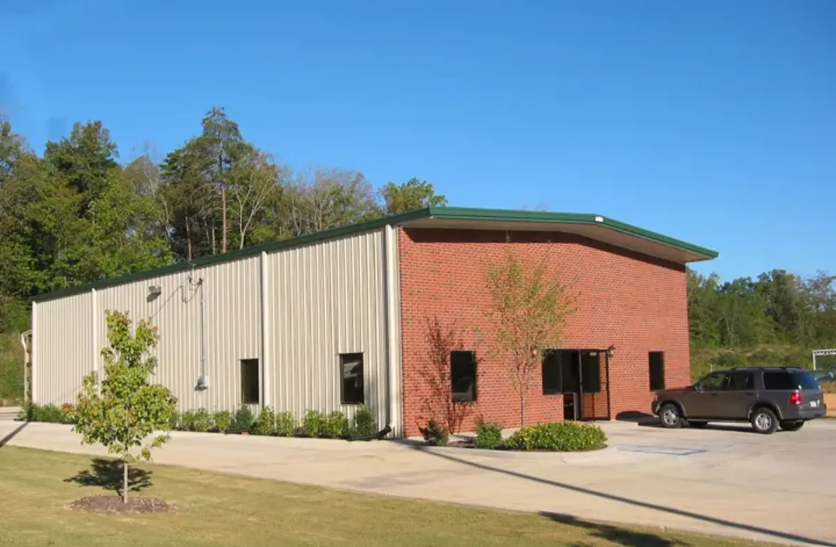 A white and red building with a green roof and a car parked in front of it.