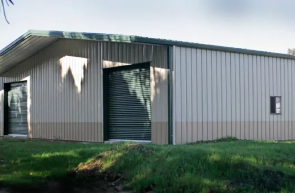 A large metal building with a green garage door and a window.
