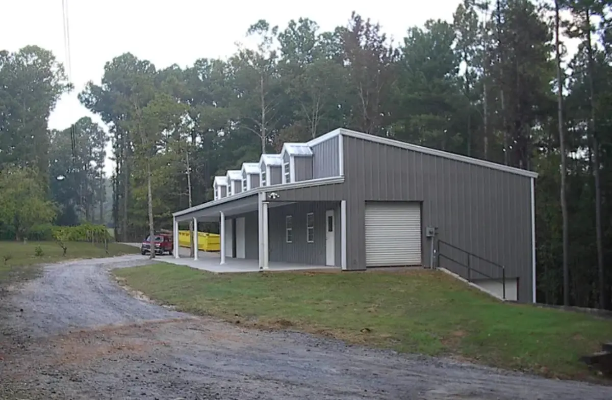 A building with a garage and a porch is surrounded by trees