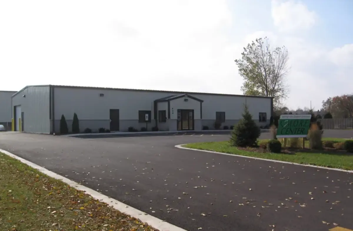 A large white building with a green sign in front of it