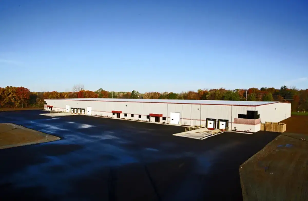 A large white building with a black driveway in front of it.