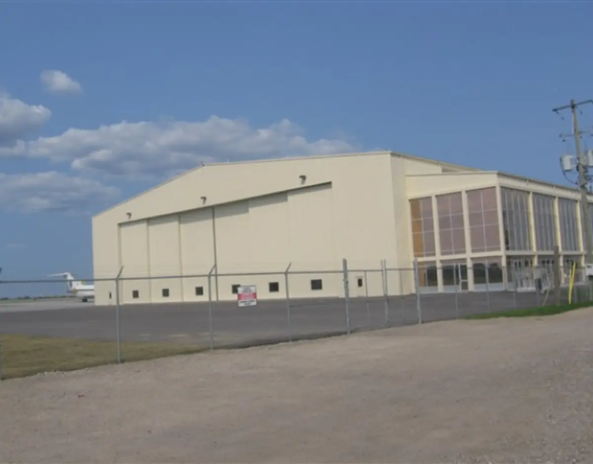 A plane is parked in front of a building with a fence around it